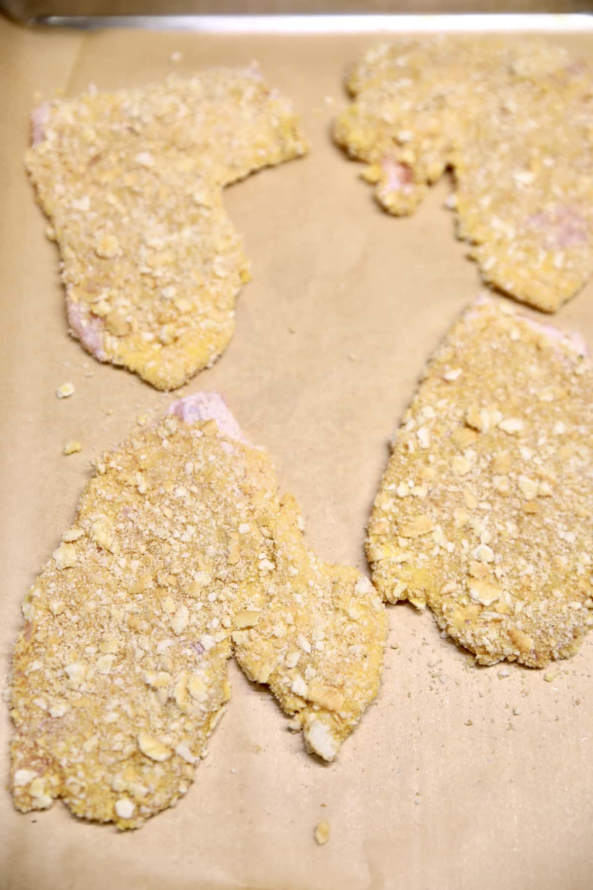 Pork cutlets on a lined baking sheet.