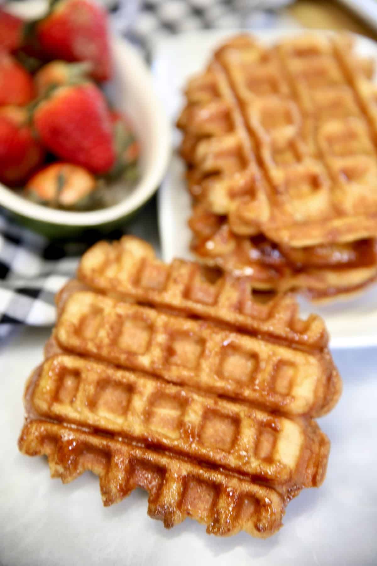 stack of croissant waffles, bowl of strawberries.