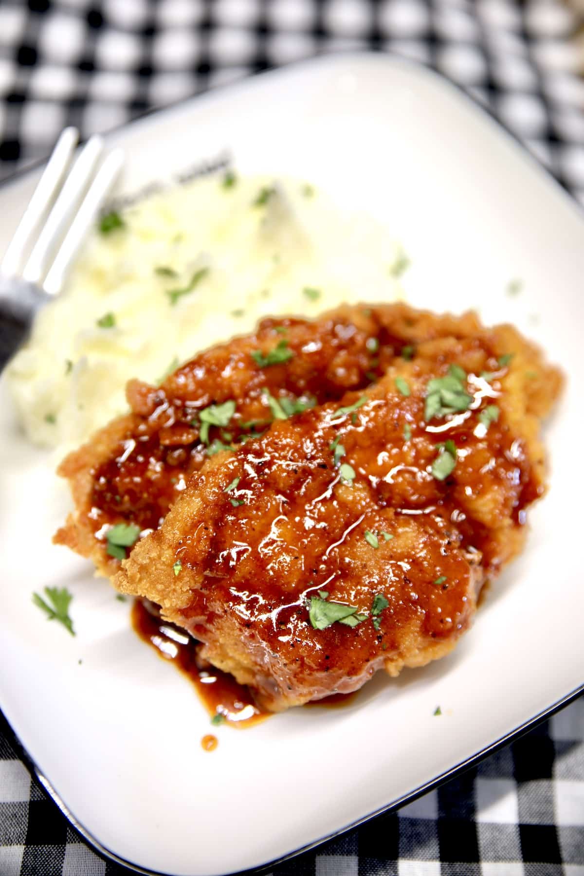 Plate with 2 crispy pork cutlets drizzled with sauce, mashed potatoes.