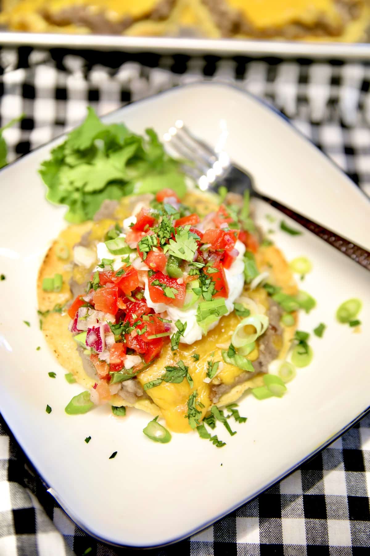 Bean tostada on a plate with sour cream, salsa.