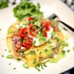 Bean Tostada on a plate with sour cream, fresh salsa.