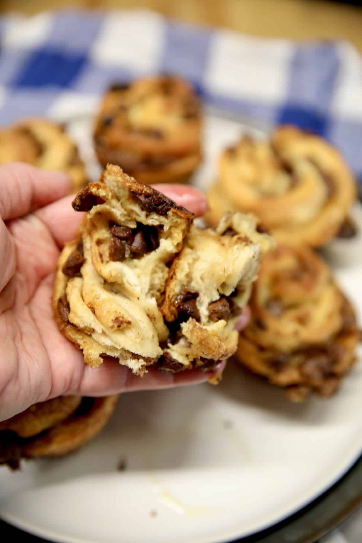 Hand holding croissant muffin with flaky inside showing. 