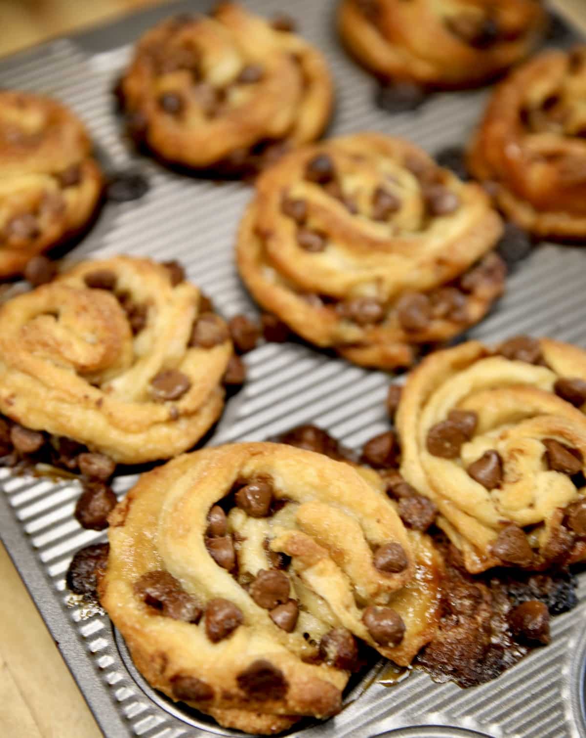 Muffin tin with baked chocolate chip croissant muffins.