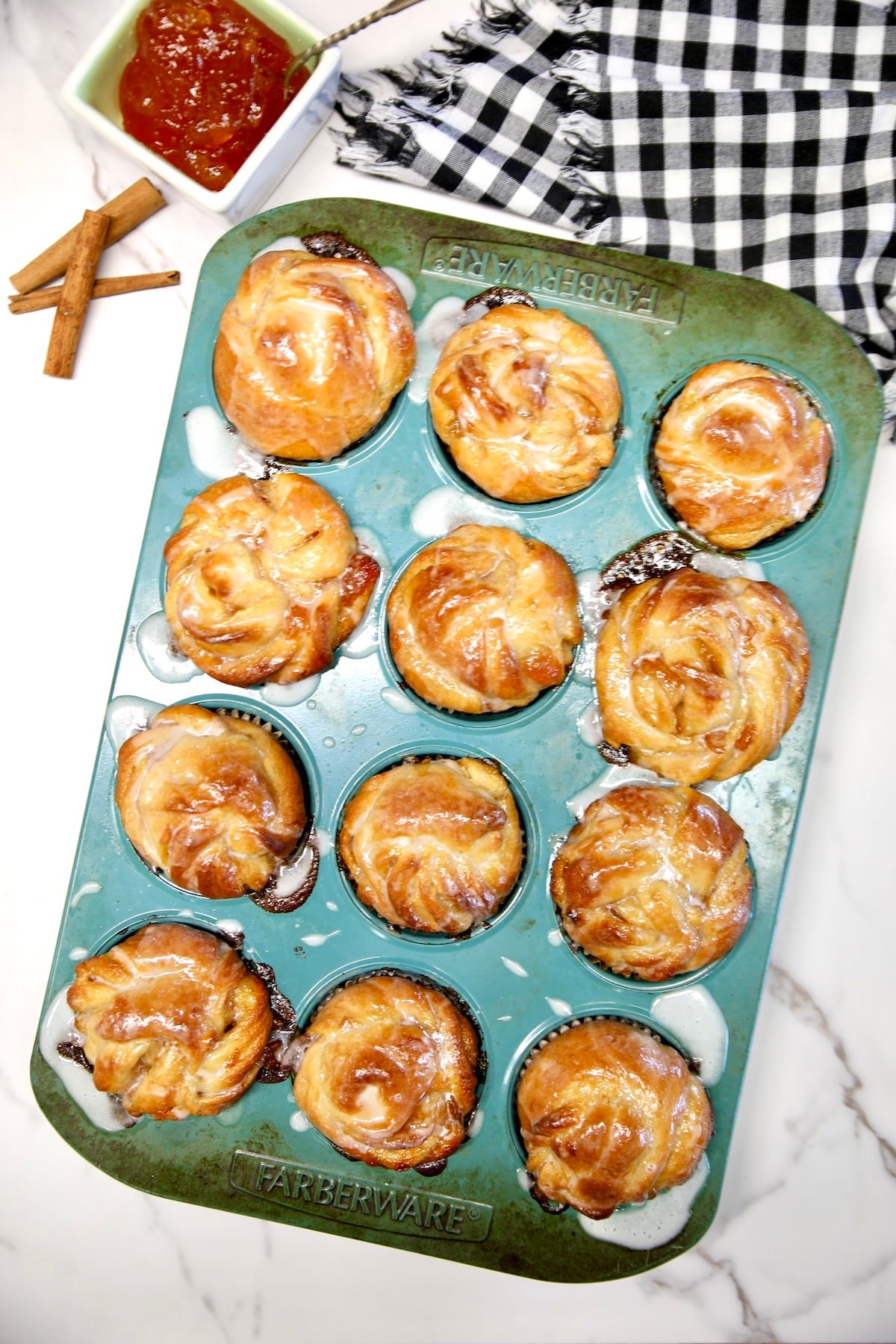 Peach pie cruffins with glaze in a muffin tin. 