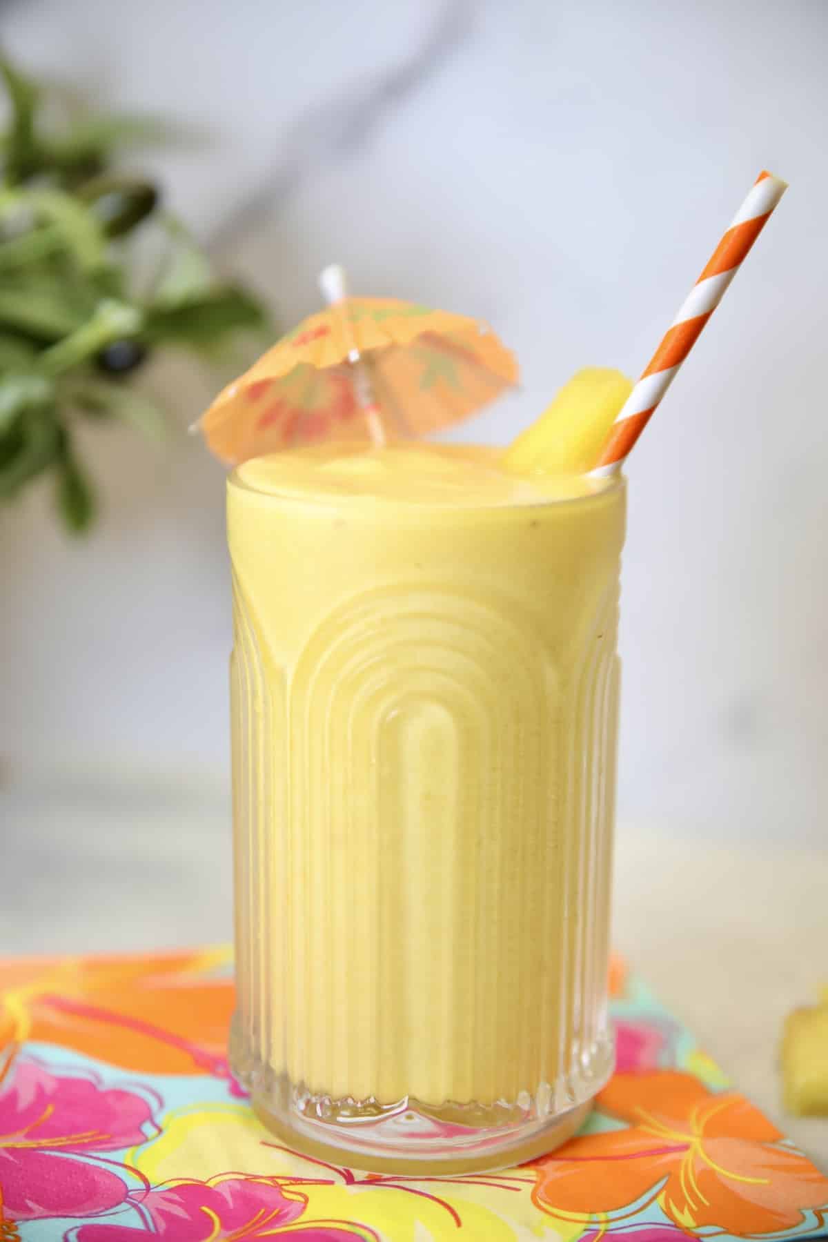 Pineapple smoothie recipe with orange juice. Pineapple smoothie with drink umbrella and straw.