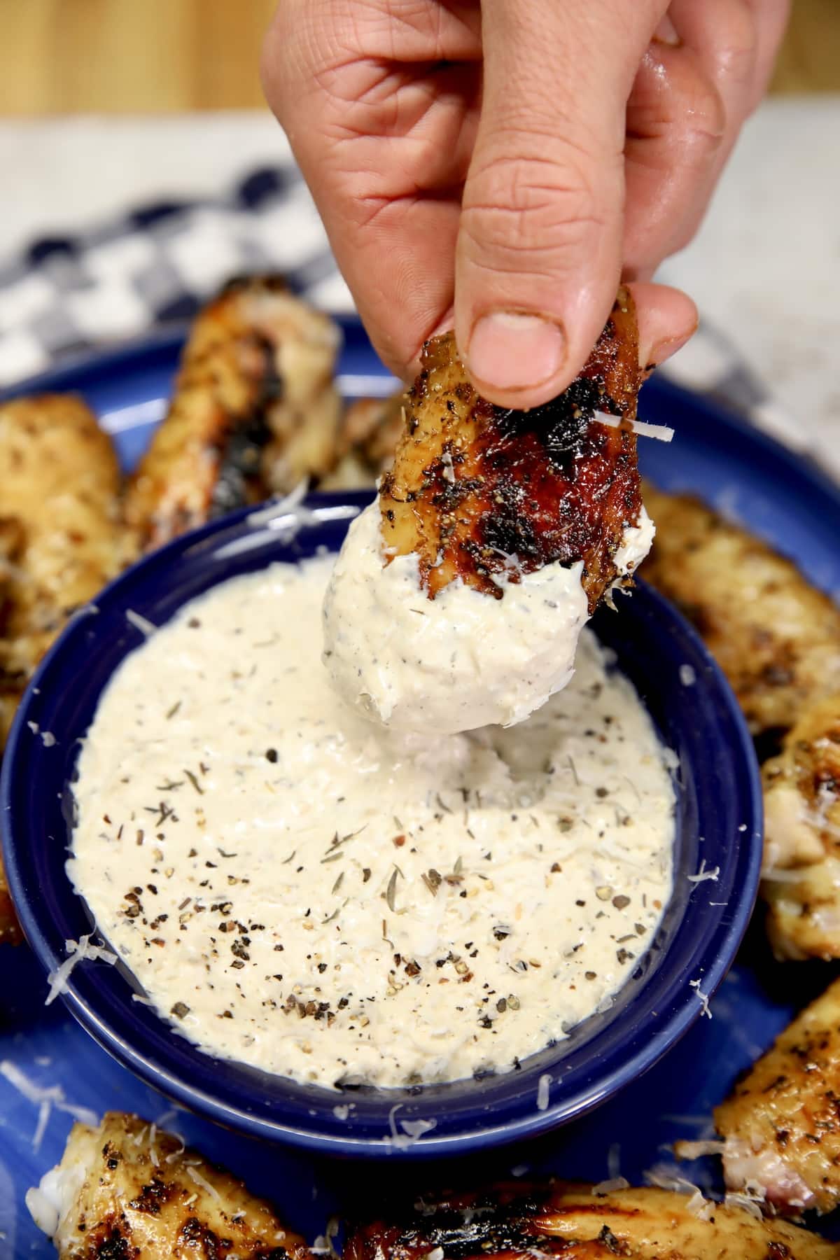 Chicken wing dipping in garlic parmesan sauce.