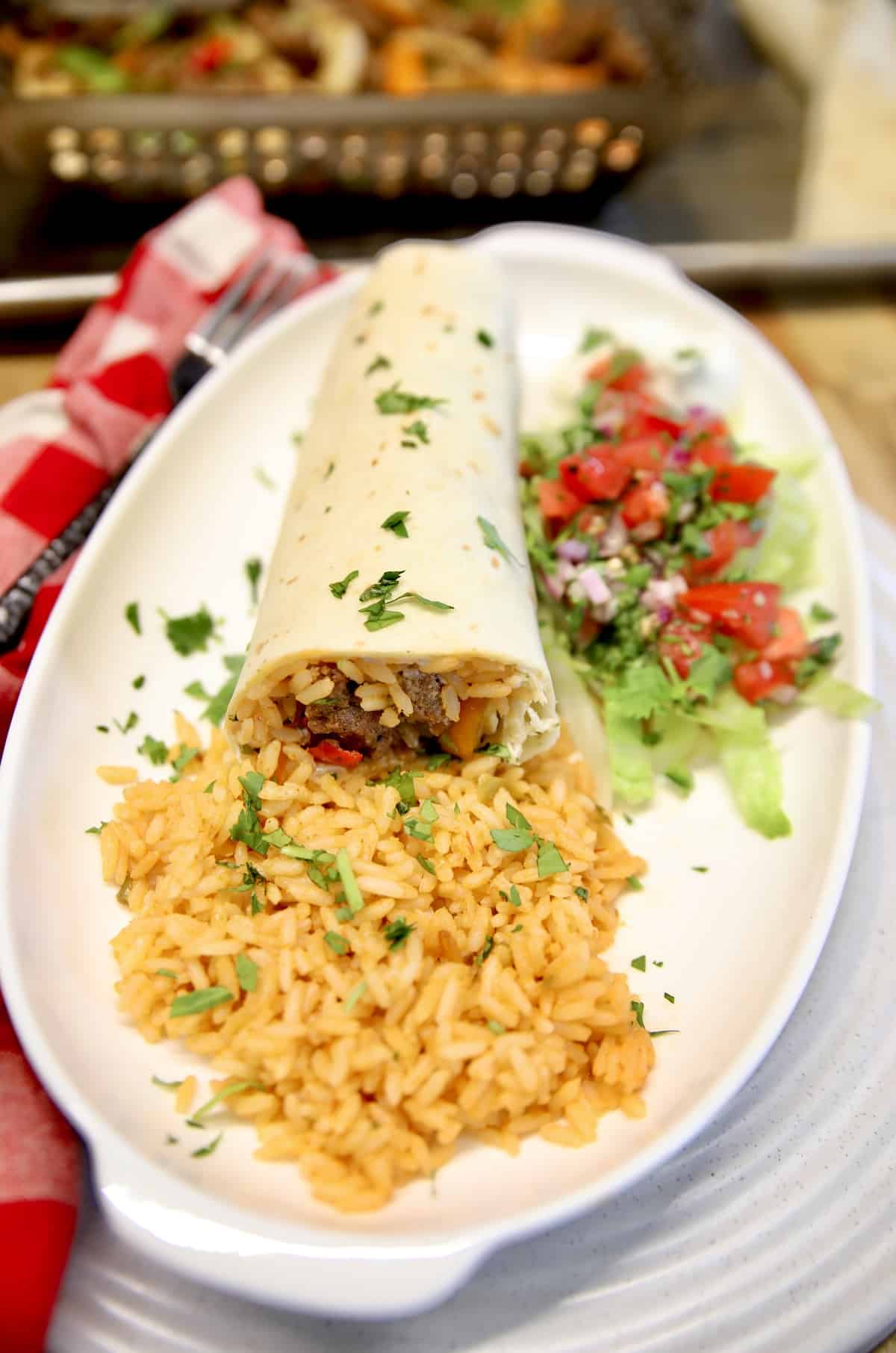 Steak burrito with rice on a platter.