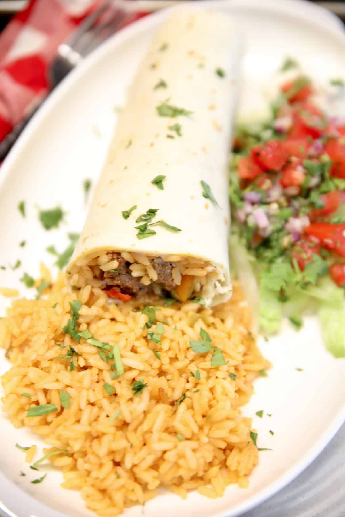 Beef and rice burritos with fresh salsa on a plate.