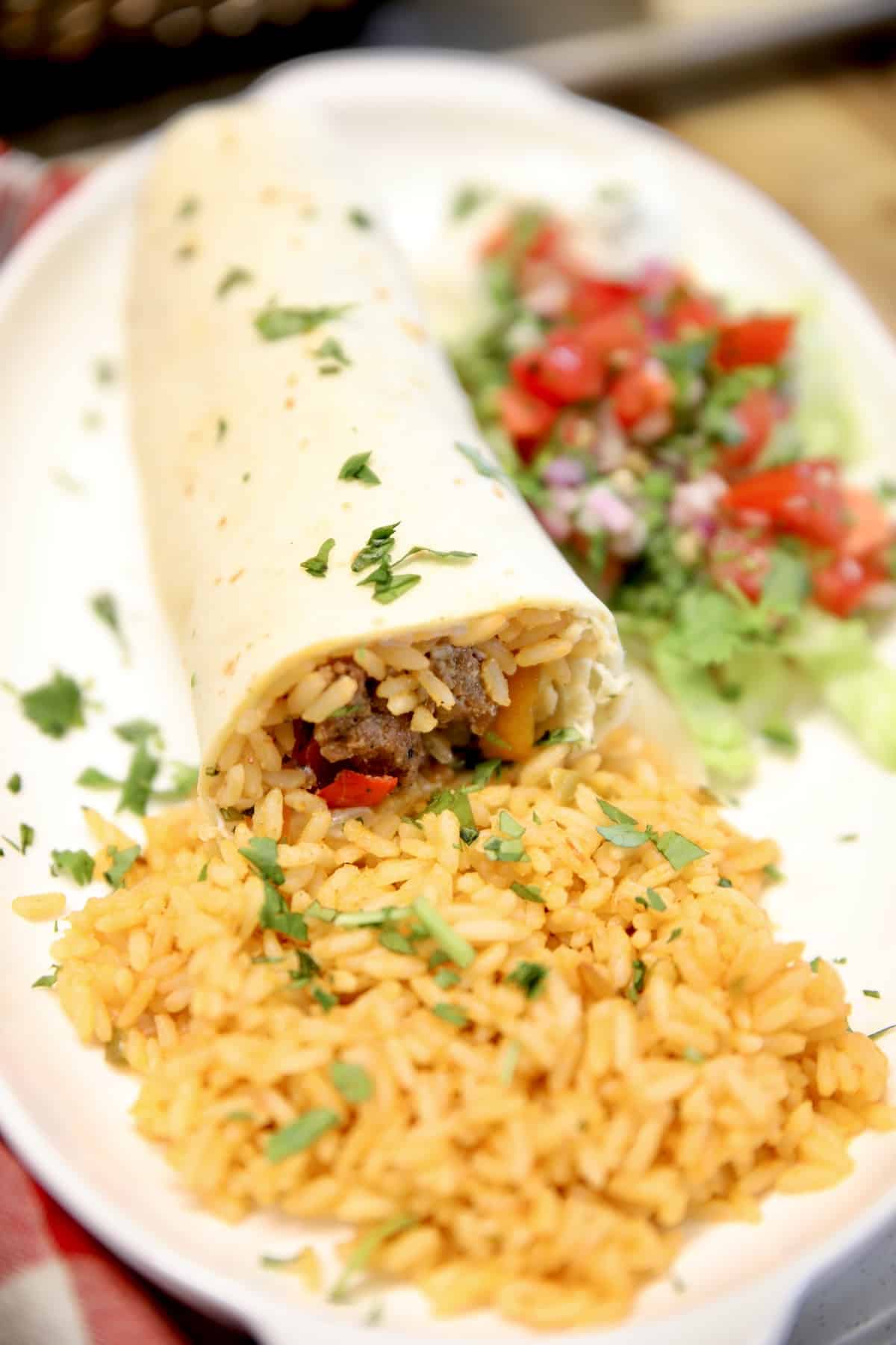 Steak burrito on a plate with rice.