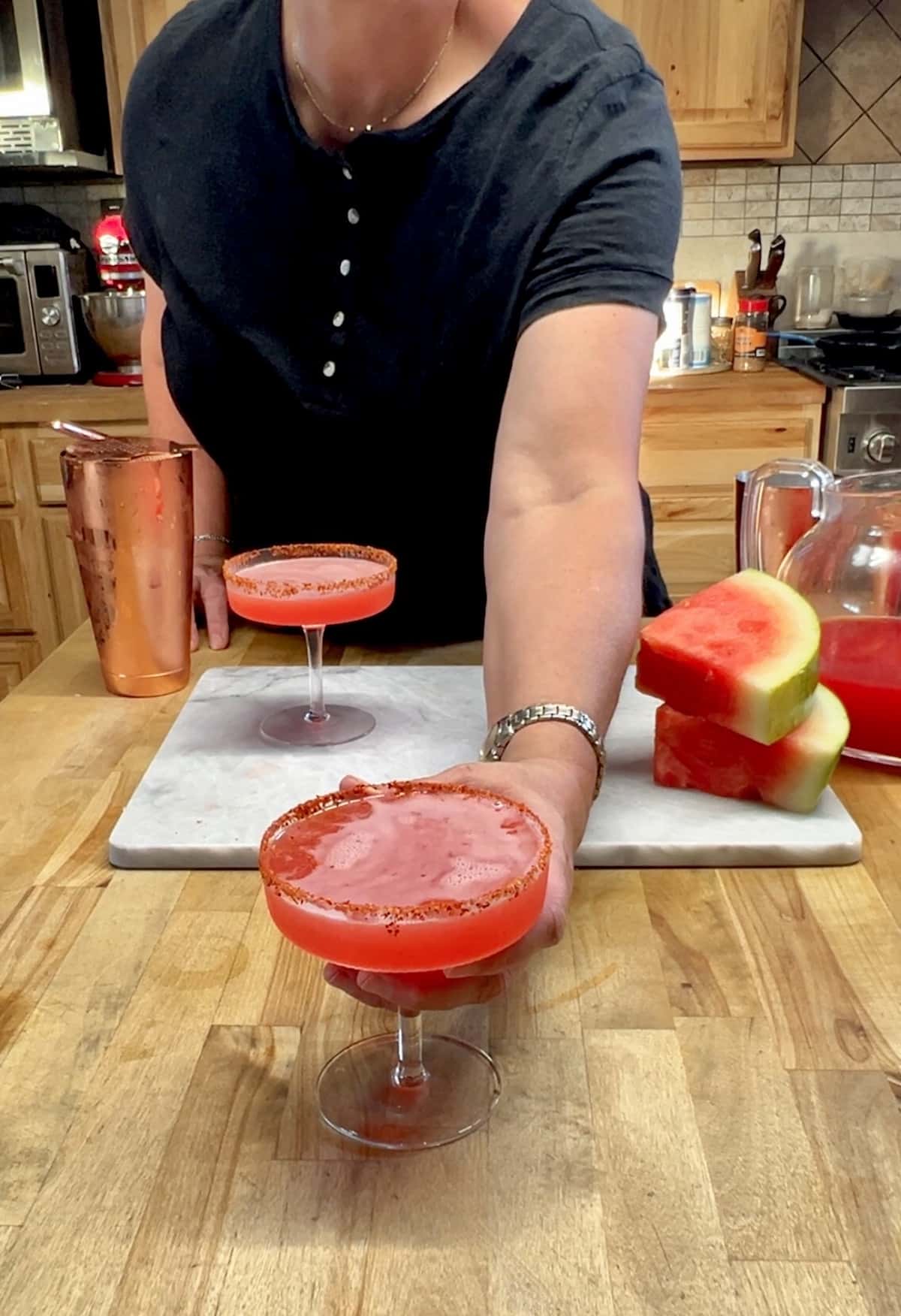 Person serving watermelon margarita in a coupe glass.