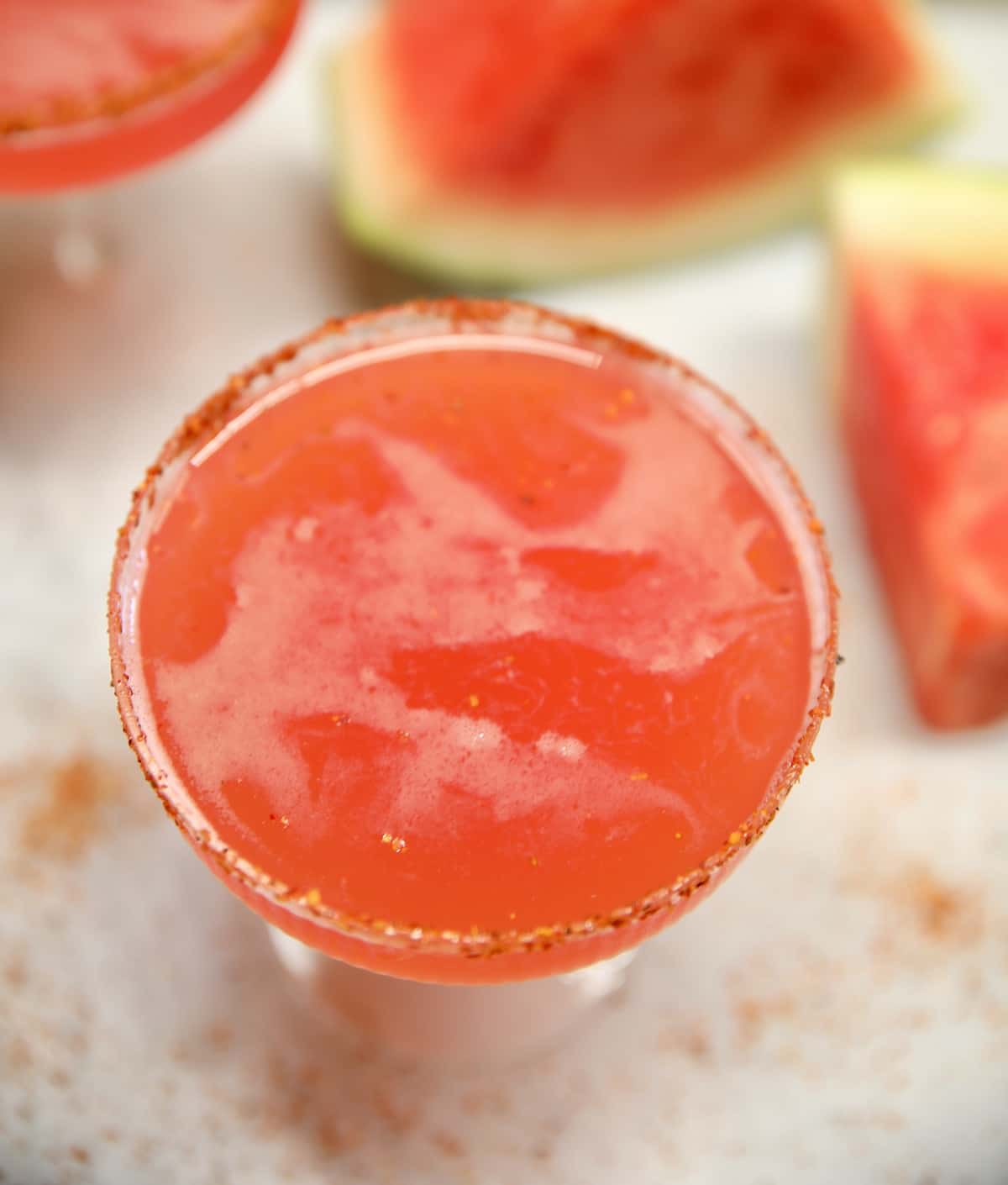 Watermelon margarita in a glass, fresh watermelon in background.