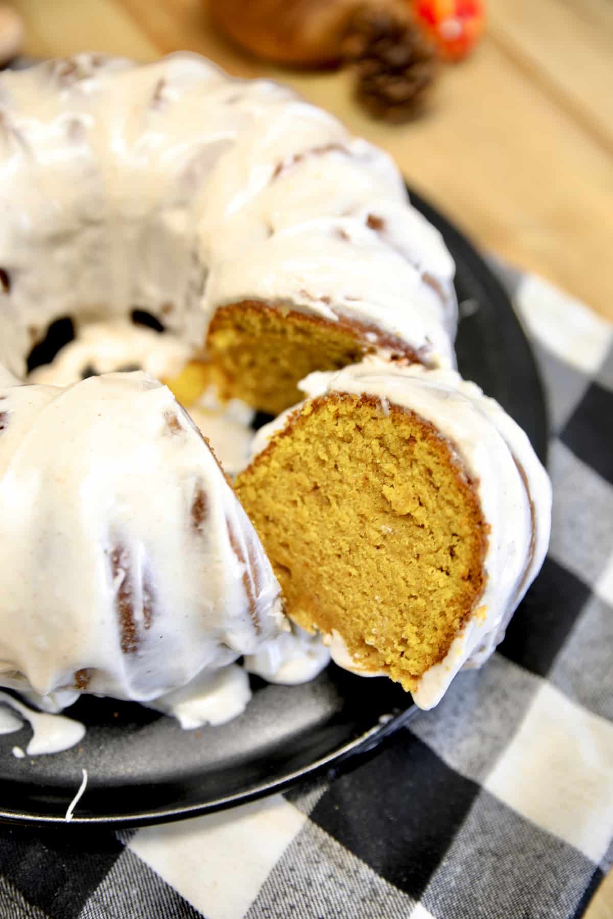 Pumpkin bundt cake with cream cheese icing. Pumpkin bundt cake with cream cheese icing, one slice cut out.