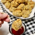 Sausage balls on a skewer dipping into maple syrup.