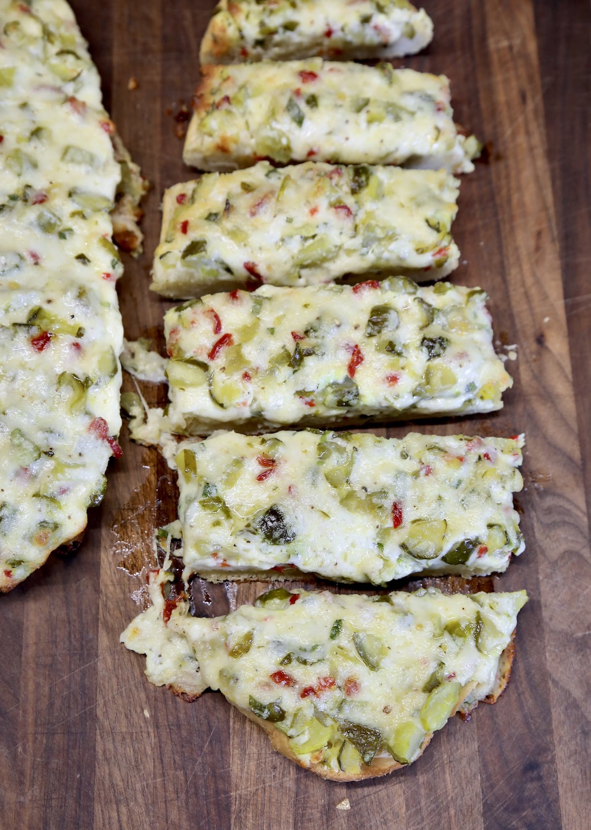 Sliced cheesy French bread with pickles.