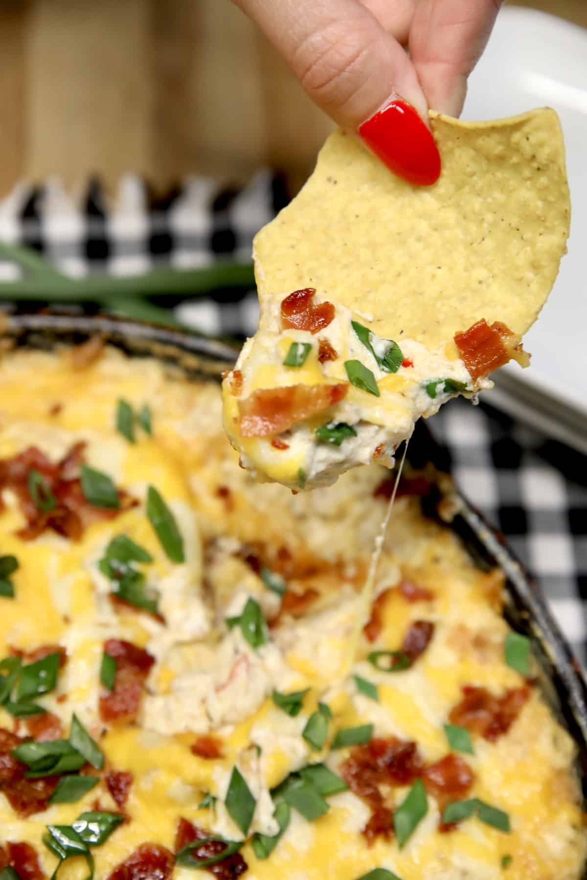 Tortilla chip dipping cheesy ham and bacon dip.