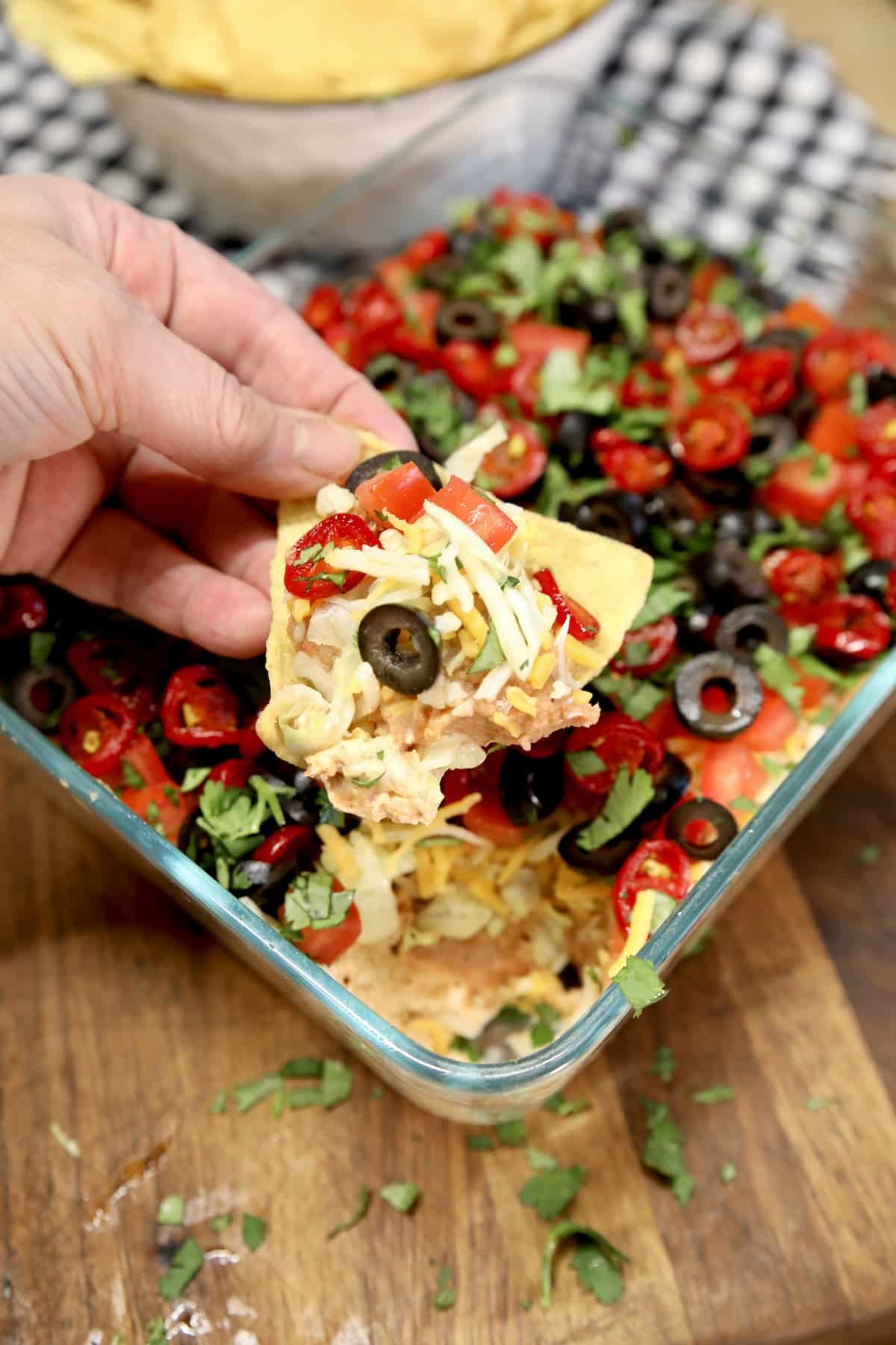 Hand holding chip with taco dip.