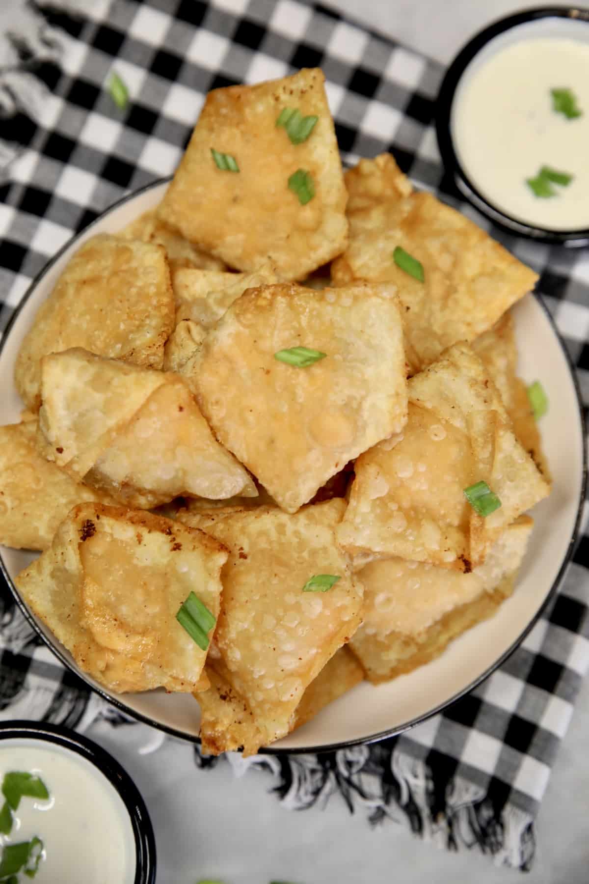 Plate of fried wontons, 2 bowls of ranch dressing.