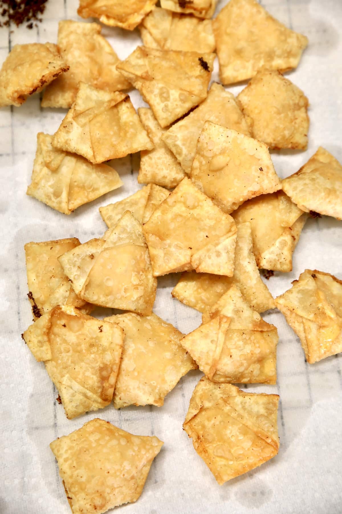 Fried wontons on a paper towel lined rack.