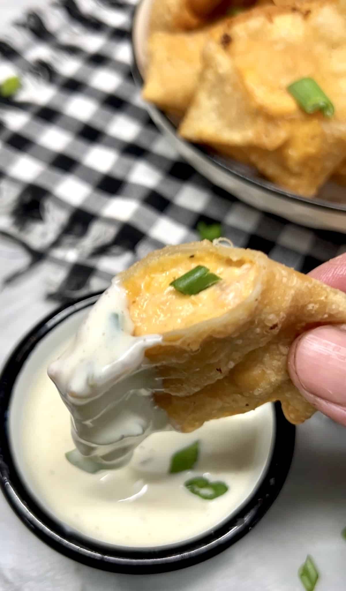 Cheesy chicken filled wonton dipping into ranch.