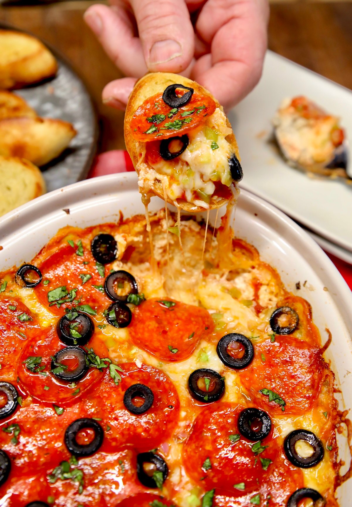 Supreme pizza dip appetizer dipping with bread.