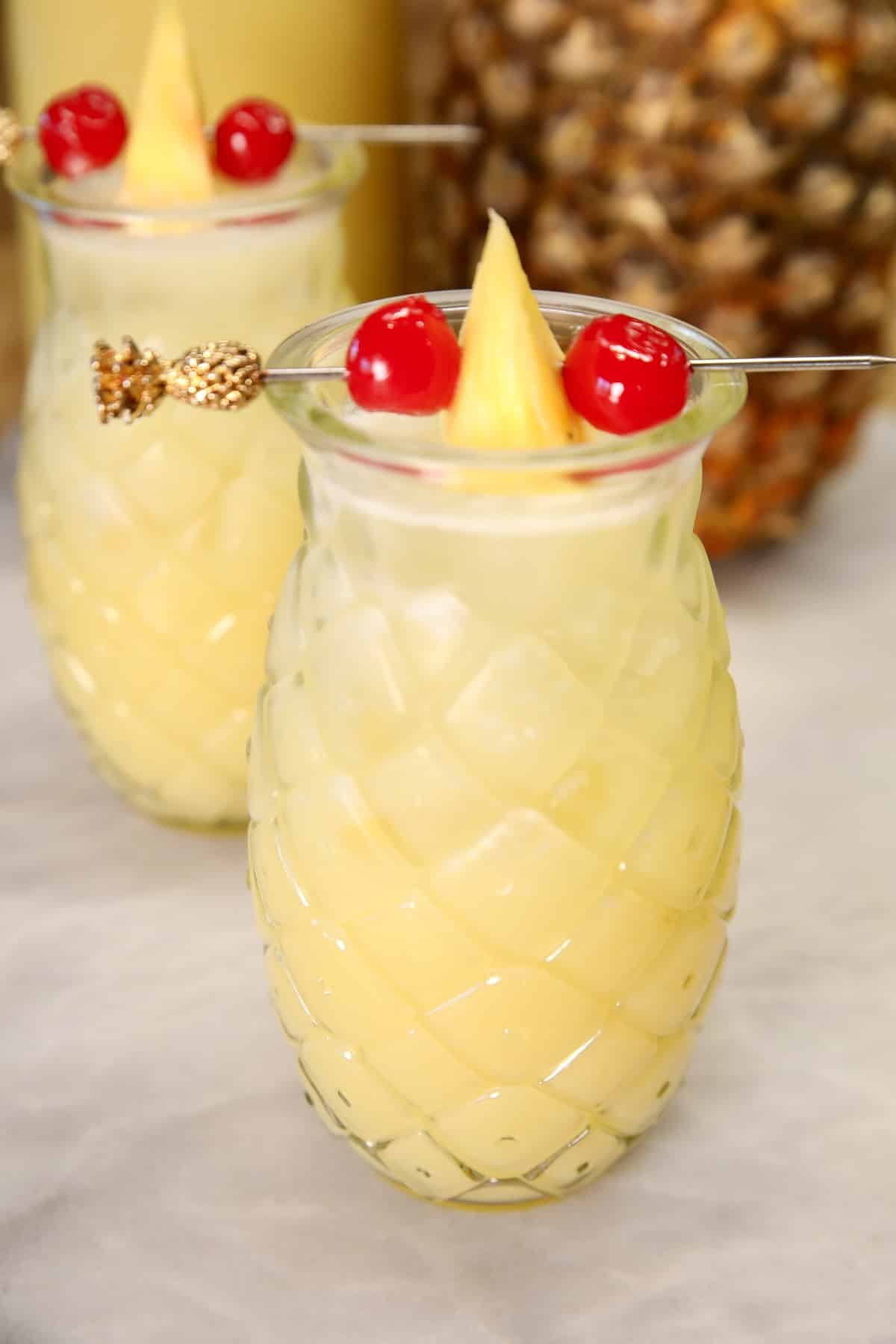 Pineapple glass with pina colada, pineapple and cherry garnish.