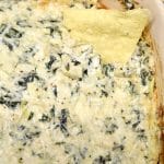 Spinach Artichoke dip in a casserole with tortilla chip.