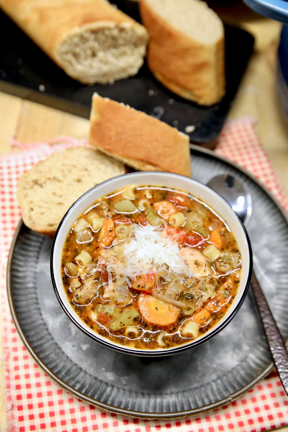 Pasta, bean and sausage soup in a bowl with bread on the side.