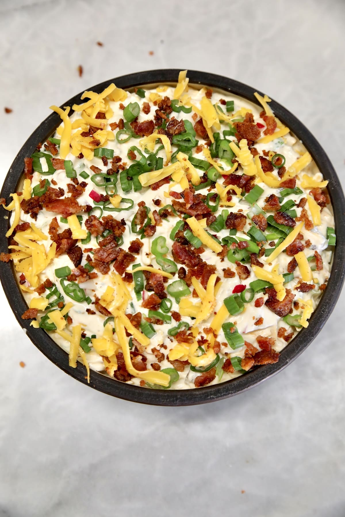 Bowl of dip with cheddar, bacon, green onions.