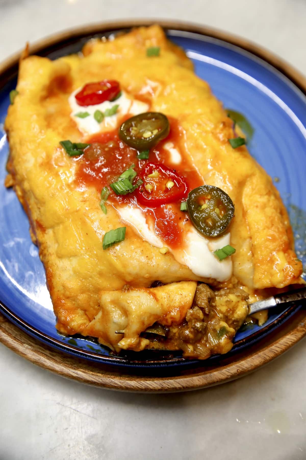 Plate of ground beef and cheese enchiladas with red sauce.