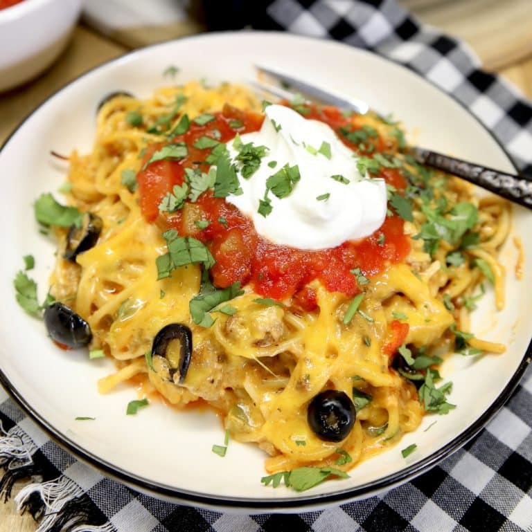 Plate of taco spaghetti with sour cream and salsa.