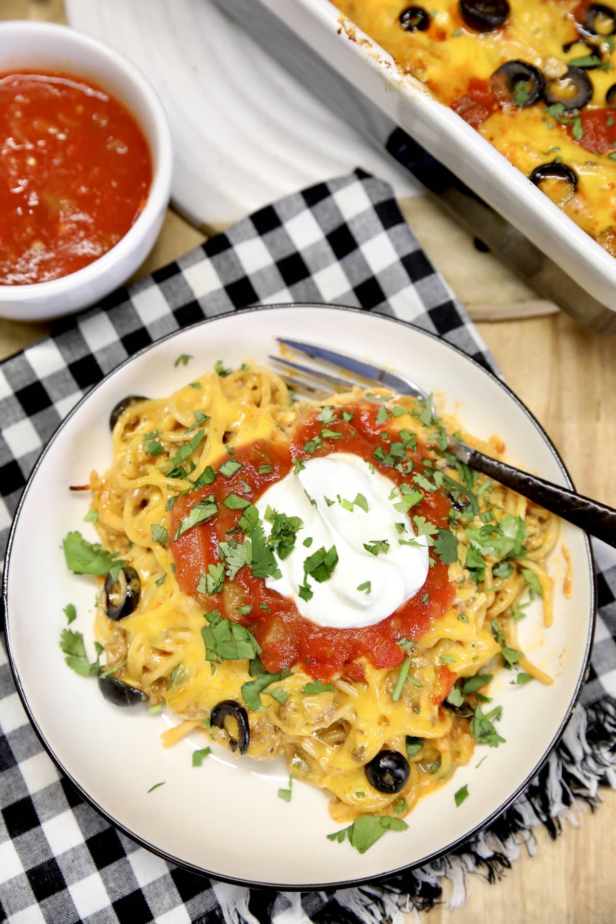 Plate of spaghetti with sour cream and salsa.