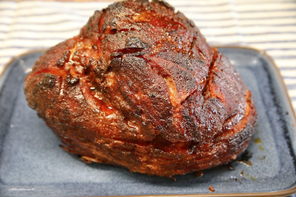 Blackberry chipotle glazed ham on a blue platter.