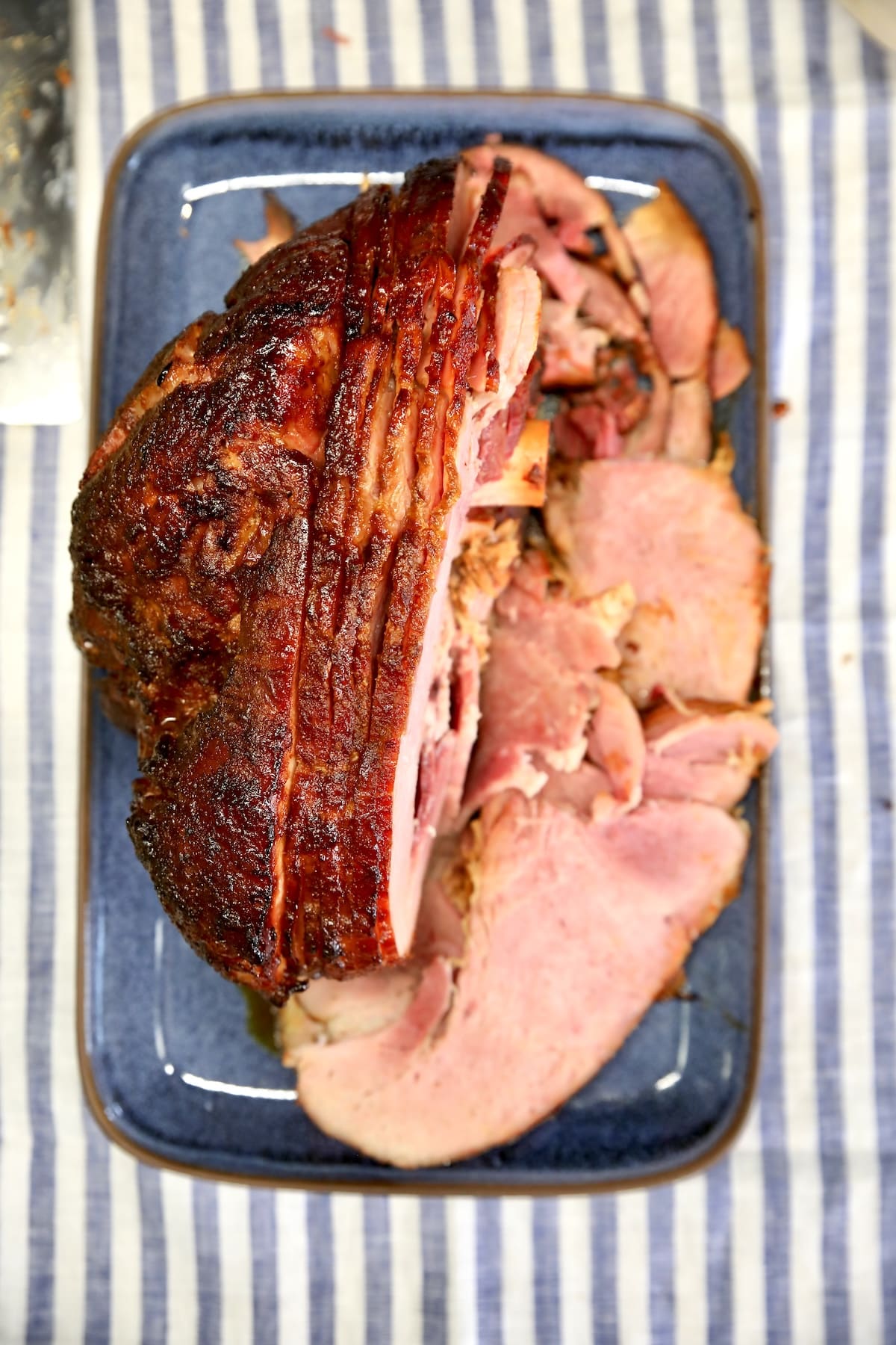 Spiral sliced holiday ham on a blue platter.