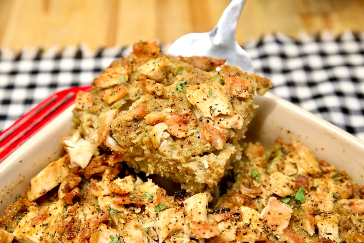 Cornbread dressing with chicken on a spatula.