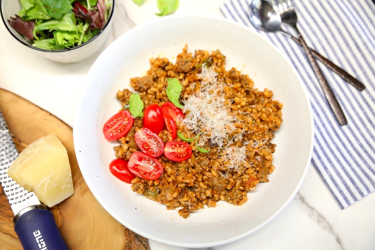 Bowl of sausage and farro with tomatoes.