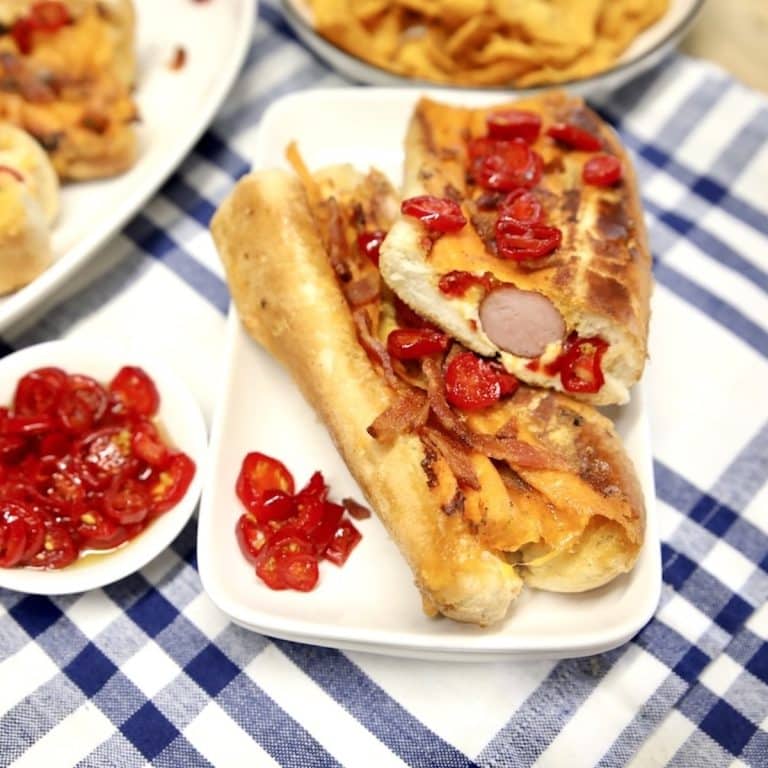 Jalapeno popper filled hot dogs on a plate.