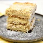 Lemon crumb bars stacked on a plate.