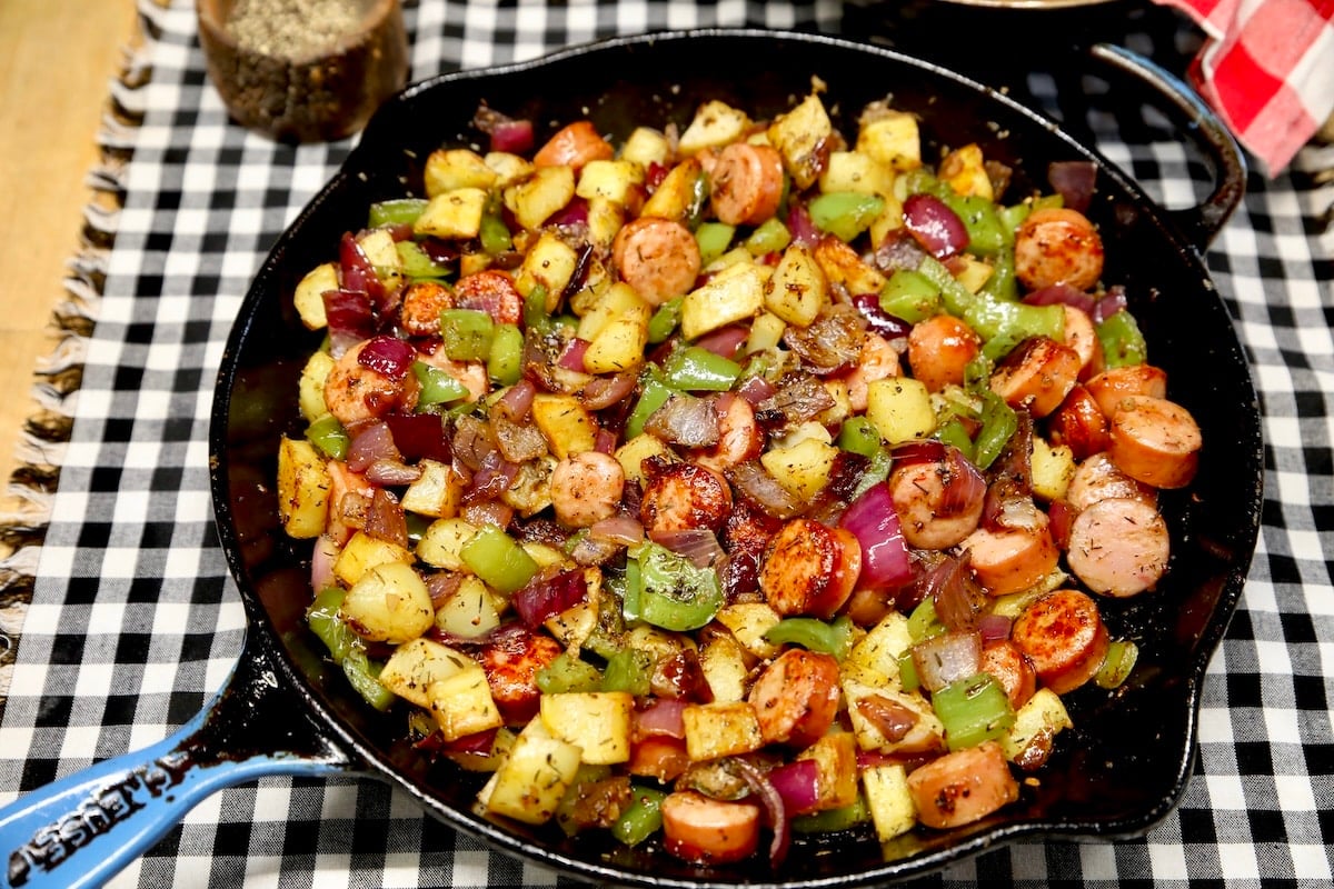 Cast iron skillet with sausage, potatoes, vegetables.