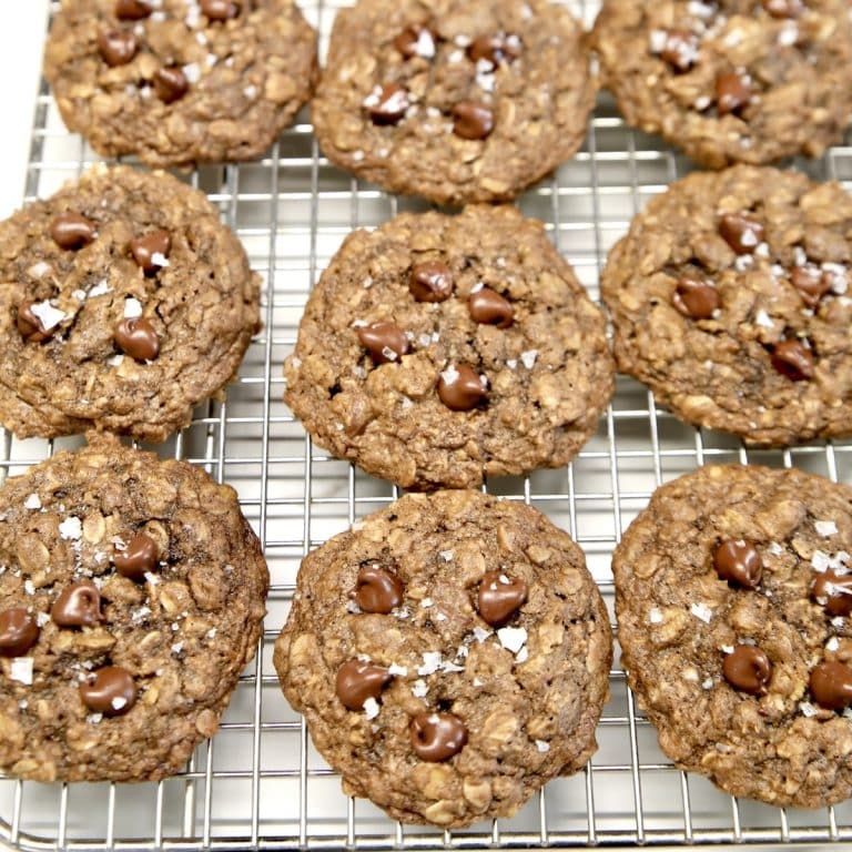 Chocolate oatmeal chocolate chip cookies with flake salt on a cooling rack.