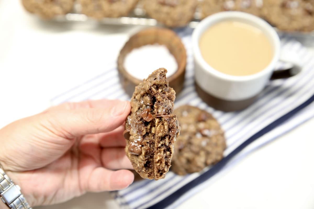 Chocolate chip chocolate oatmeal cookie in hand - middle showing.