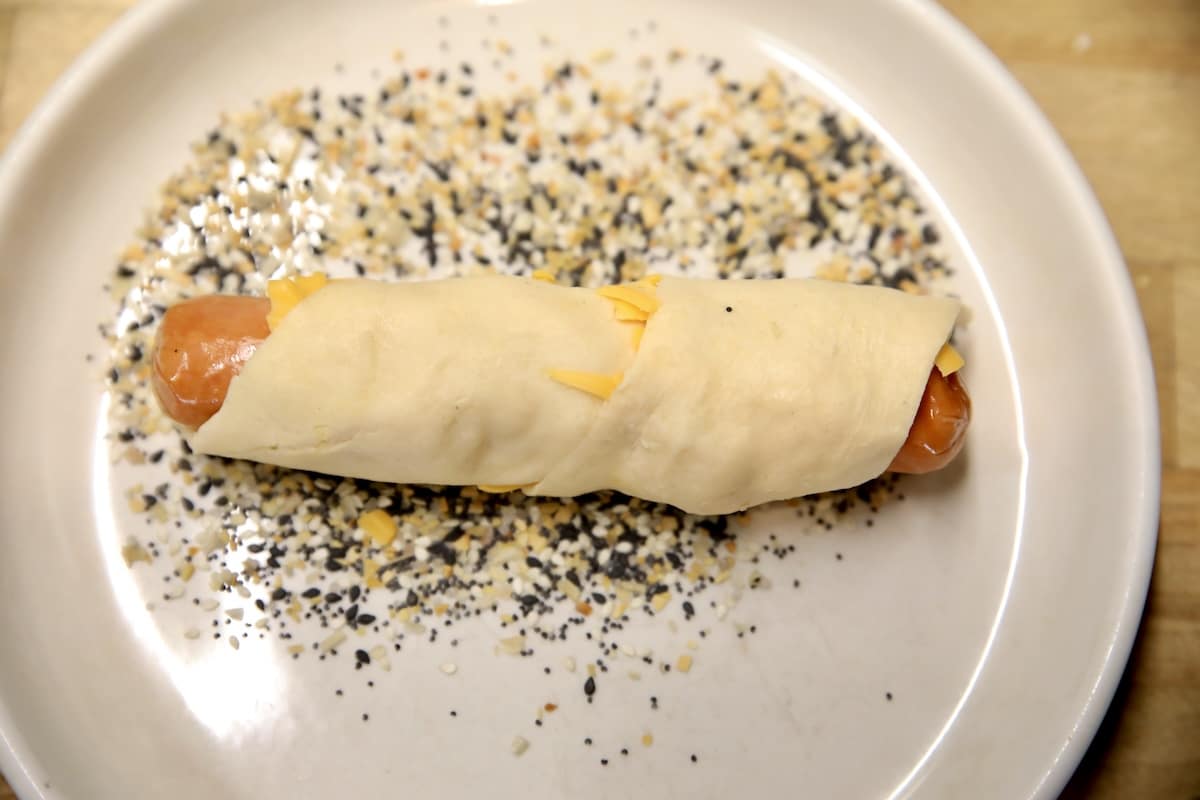Rolling crescent wrapped hot dog in everything bagel seasoning.