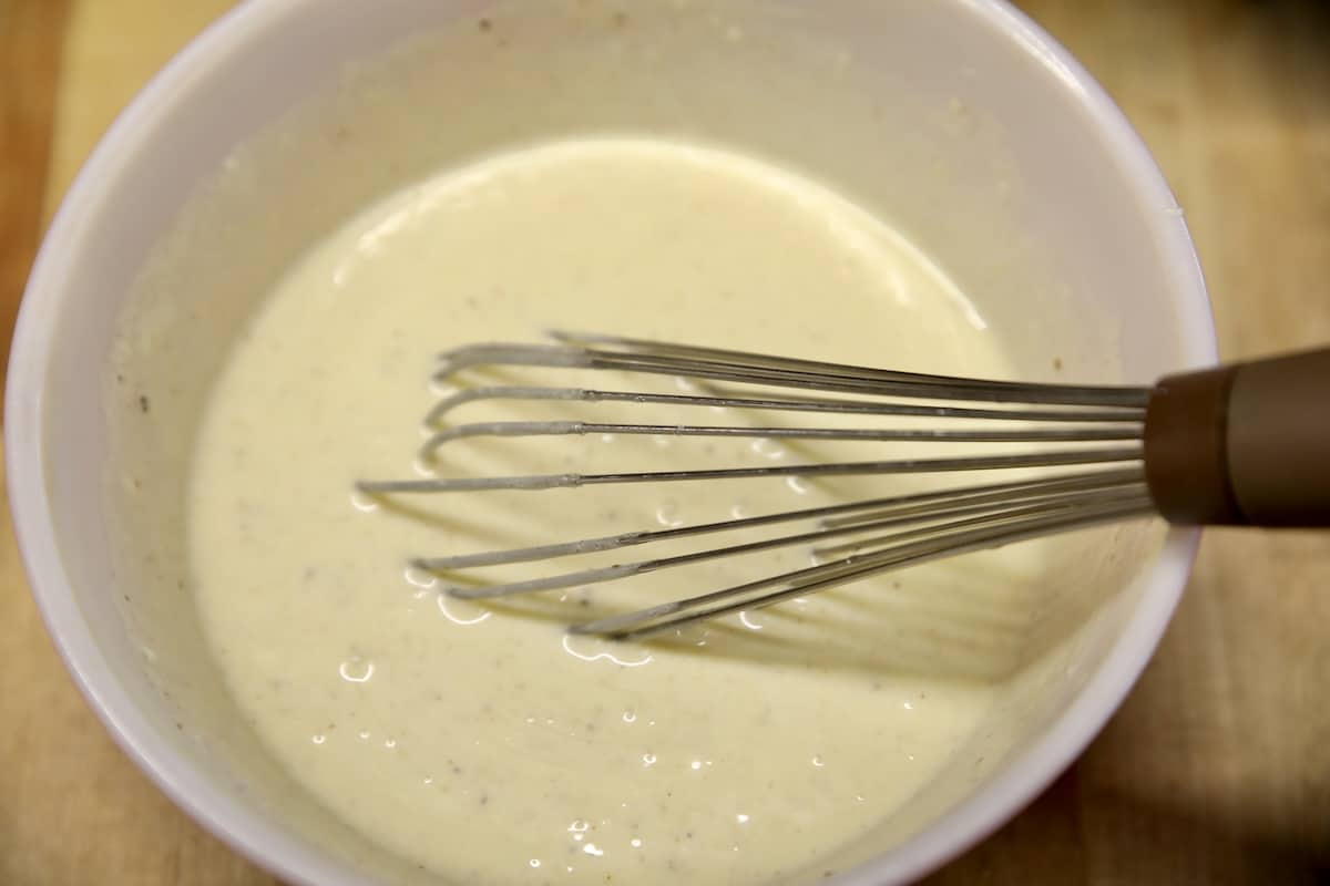 Creamy dressing mixed in a bowl with whisk.