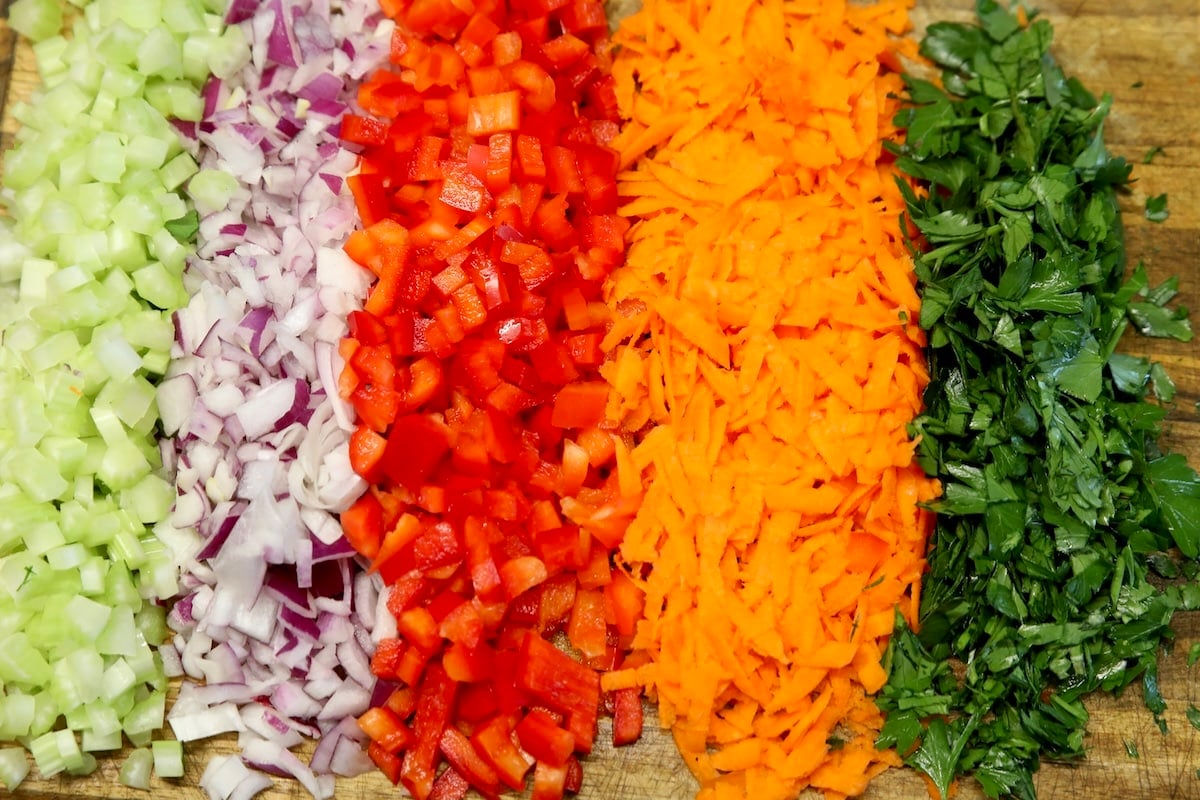 Chopped vegetables and parsley on a cutting board.