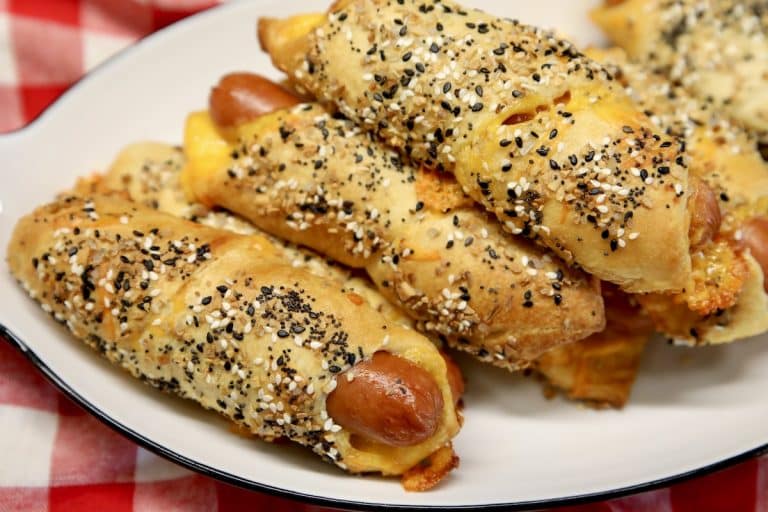 Pigs in a blanket with crescent dough and everything bagel seasoning on a platter.