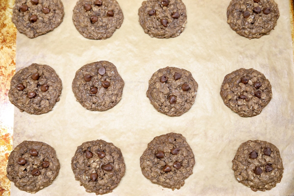 Chocolate oatmeal cookies with chocolate chips on baking sheet.