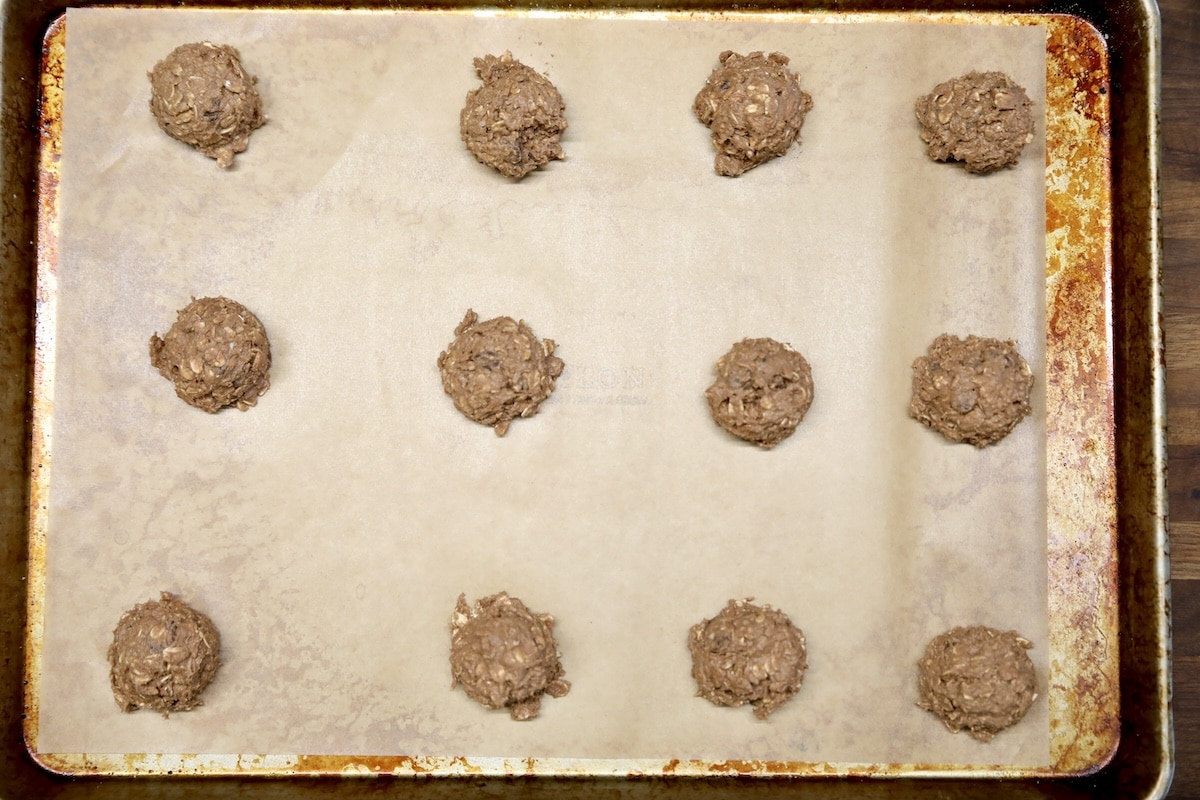 Chocolate oatmeal cookie dough on parchment lined baking sheet.