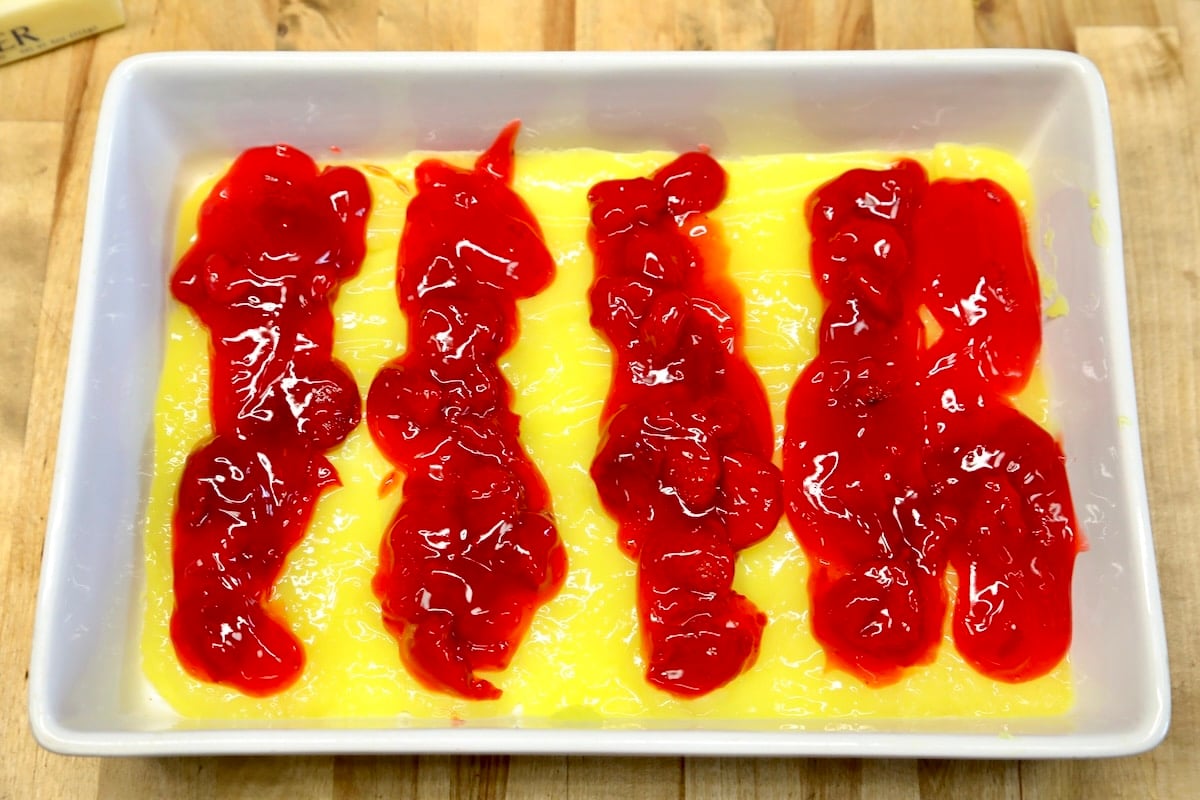 Strawberry pie filling spooned over lemon pie filling in a baking dish.