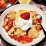 Dump cake on a plate with strawberry and lemon.