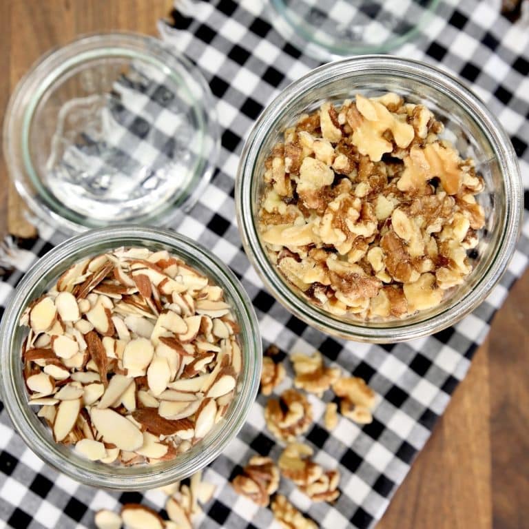 Toasted sliced almonds in a jar, toasted walnuts in a jar on checked napkin.