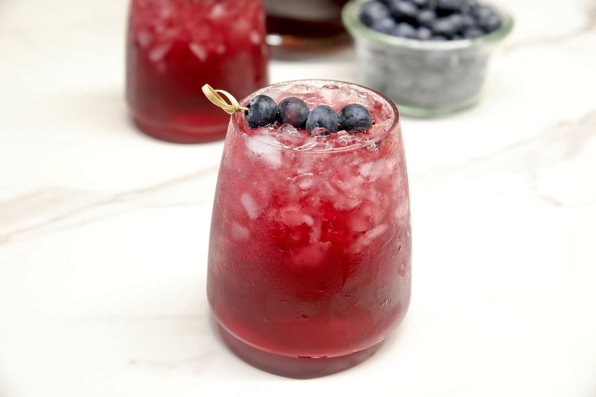 Blueberry sangria in a stemless glass- blueberry garnish.